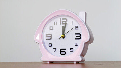 Pink House-Shaped Alarm Clock on Wooden Surface.
