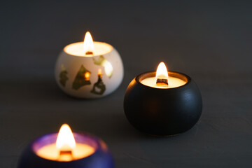 Three white candles burn in a various plaster cups against a soft gray background, creating a calm and elegant atmosphere. Perfect for relaxation, meditation, or minimalist design themes.