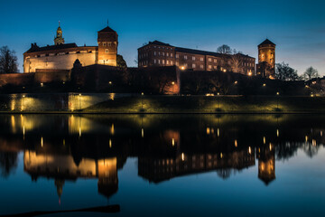 Poland, Krakow: Royal Castle of Wawel by morning blue hour with reflection in water