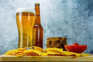 Lager beer and snacks on stone table. Cracker, chips side view