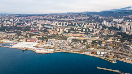 An aerial drone photo showcases ZTC Mall Rijeka along the stunning Adriatic coastline, capturing a breathtaking view of the cityscape. In the background, the newly developed Rijeka cargo terminal