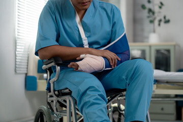 Patient recovering from injury, seated in wheelchair with arm sling and bandage, surrounded by...