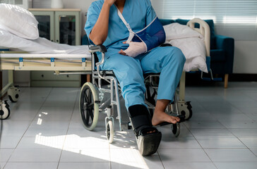 Hospitalized patient recovering in wheelchair, wearing arm sling and ankle brace, focusing on rehabilitation after medical treatment or injury