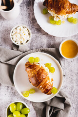 Croissant with ricotta, grapes and honey on a plate on a table top and vertical view