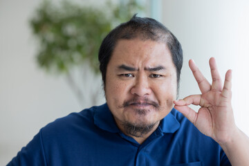 Fototapeta premium Angry upset Middle aged asian man asking you to keep quiet with zip it or shut up gesture