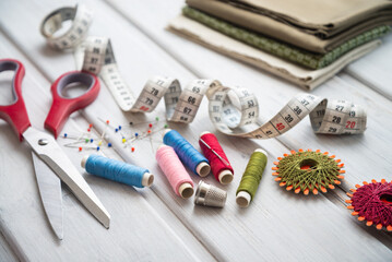 Sewing utensils - colored spools of thread, fabrics, tape measure and thimble