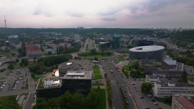 Aerial perspective showcases Vilnius city center, featuring Nasdaq Vilnius stock exchange, a meandering river, vibrant greenery, and the prominent TV tower in the background