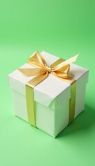 Obraz premium Simple yet stylish gift container wrapped in plain white paper with a delicate golden ribbon bow on soft green background, stylish, green background
