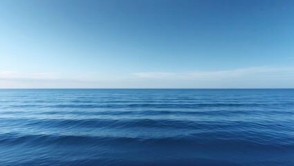 Obraz premium A serene ocean view featuring calm blue waters and a clear sky reflecting soft light. The horizon creates a tranquil atmosphere