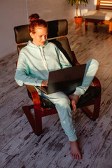 Smiling young woman or teenage girl browsing at his laptop at home