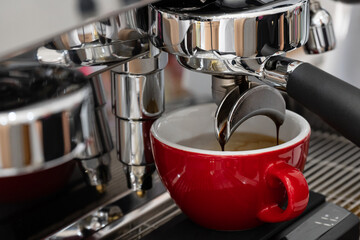 Professional espresso coffee machine while preparing espressos coffee red cup.Close-up of black coffee menu pouring from the coffee machine in cafe.