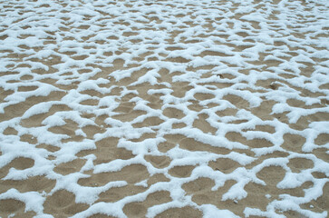 Fresh white snow in patches on sand