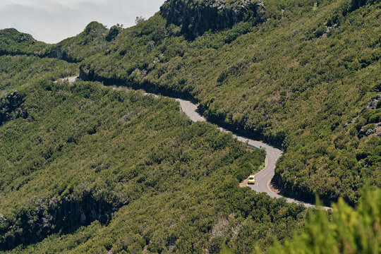 Strada che divide in due una pendice montuosa colma di vegetazione.