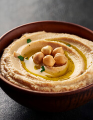 Bowl of hummus with olive oil swirl and chickpeas on top, macro shot