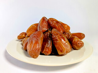 close-up view of fresh, shiny dates stacked on white plate isolated on white background