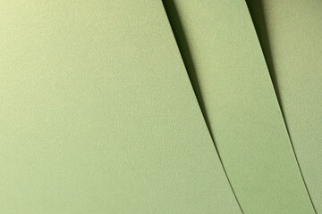 Muted olive green paper background with a smooth matte texture and layered folds. Soft sage and...