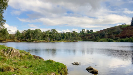 Scenic view of Tarn Hows in the Lake District, Cumbria, UK, featuring trees, hills, and calm water, ideal for travel and nature projects.
