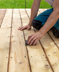 Man is sanding a wooden deck