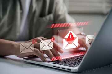 Spam email alert danger concept. person typing on laptop receives scam notification, illustrating...