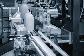 Machine makes white plastic bottles. Bottles are produced on a factory conveyor, industrial concept