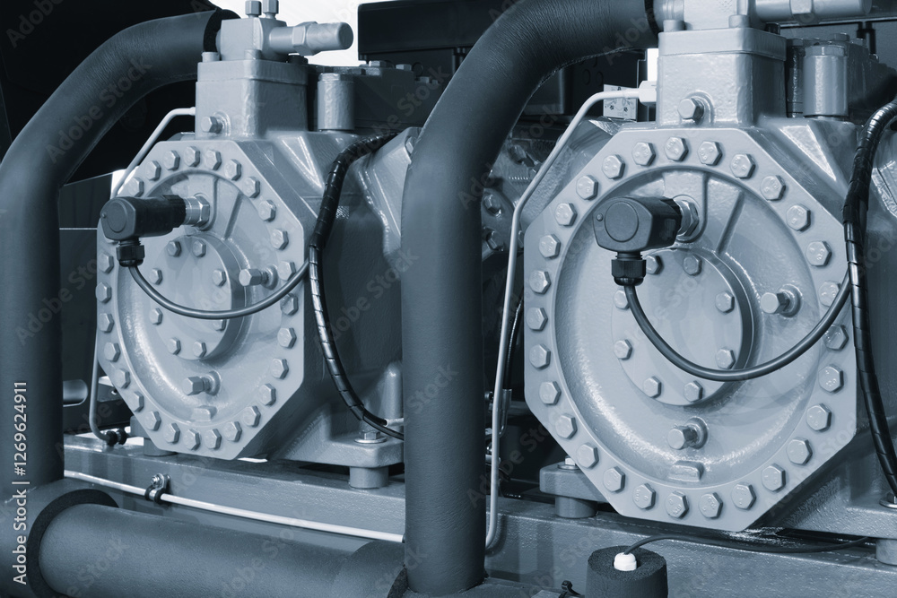 Poster two large gray and black industrial machines with many bolts and screws. the machines are connected 