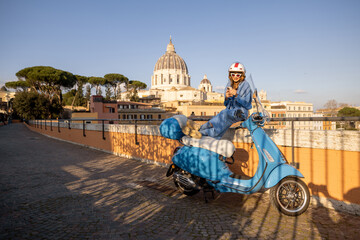 A stylish traveler enjoys the golden hour in Rome, sitting on a vintage scooter near St. Peters Basilica. Perfect for themes of travel, freedom, Italian lifestyle, and urban exploration © rh2010