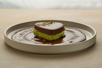 Close up of a dark Dubai chocolate dessert served in a plate against a blurred background. Beautiful modern luxury set up with soft light