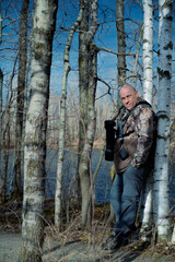 Obraz premium A man with a camera, with a hunting coat is resting in a birch grove