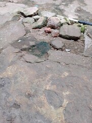 Damaged concrete surface with rocks and moss, depicting decay and neglect