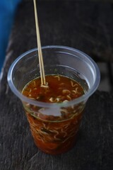 Aromatic spicy noodle cup with chopsticks, a quick meal on a wooden table