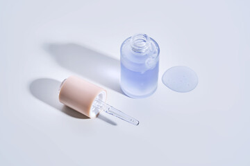 Cosmetic bottle, dropper and a drop of serum on a white background.