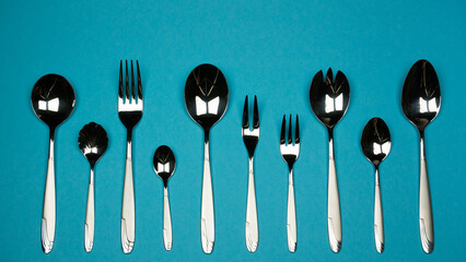 Forks and spoons from small to large in one row on blue background