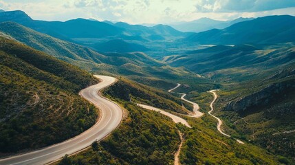 Dramatic Aerial View of Curving Asphalt Road in Mountain Landscape