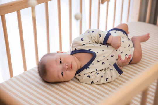 Little baby resting in wooden crib safely