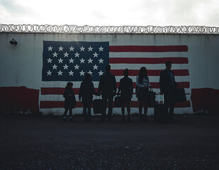 United States migrant crisis and US immigration or USA refugee concept as people on a border wall with an American flag as a social issue about illegal aliens or immigrants camp