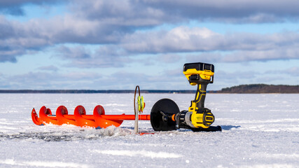 Power Drill with Ice Auger for Ice Fishing on a Snowy Lake.