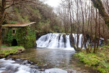 Paisaje de cascada con agua efecto seda y antiguo molino de piedra llena de musgo 