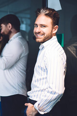 Cheerful businessman standing with coworkers in office hall