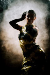Dancing silhouette of a latina woman expressing movement in smoke during a dark performance at an energetic dance event