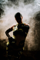 Obraz premium Dancing silhouette of a latina woman in smoke, showcasing bachata and rumba moves during an evening performance