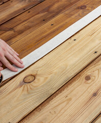 Person is applying tape to a wooden surface