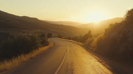Winding road stretches through mountainous landscape under a golden sunset