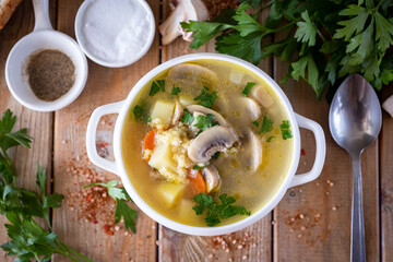 Hot mushroom soup with vegetables in a white plate on a wooden table. Mushroom soup for lunch. View from above. Close-up.