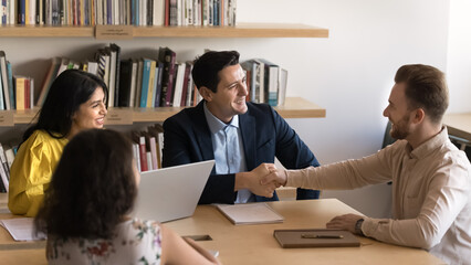 Well done. Happy proud young professor tutor handshake millennial male student on group seminar praise for successful problem solving acknowledge effective research work motivate for future challenges
