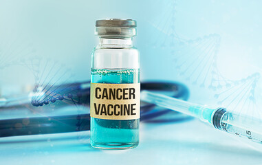 A bottle of cancer vaccine is on a table next to a syringe
