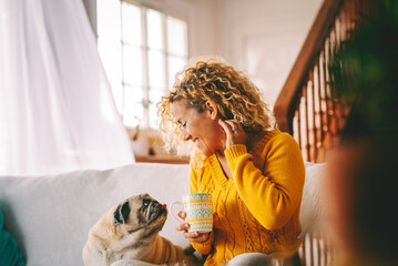Adult female relaxes on a comfortable sofa at home while engaging with her beloved pug to share...