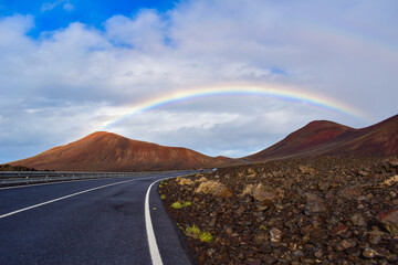 Driving with rainbow over volcanic mountains landscape, iLanzarote, Canary Islands
