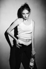 Portrait of bad girl with cigarette and bottle of alcohol (vodka). Smoking young woman stands at the wall. Black and white