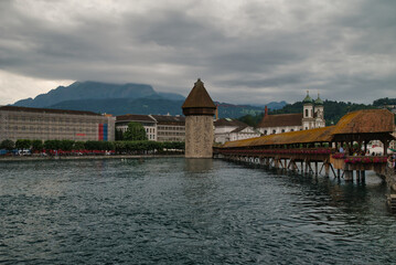 Fototapeta premium View of the Kapellbrücke bridge a bridge spanning the Reuss river in the city of Lucerne (Switzerland), during a cloudy day in spring. 