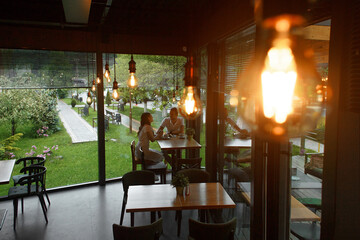 couple sitting at a table in a cafe with large panoramic windows. A woman and a man are sitting opposite each other, talking and holding hands.